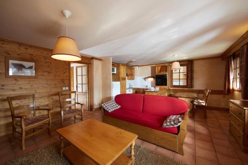 a living room with a red couch and a table at CGH Résidences & Spas les Chalets du Soleil Authentiques in Les Menuires