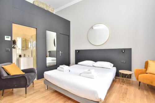 une chambre avec un grand lit blanc et deux chaises dans l'établissement Cosy apartment - 2BR-7P - Arc de Triomphe, à Paris
