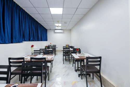 a dining room with tables and chairs and blue curtains at Vanusa Residency in Bengaluru