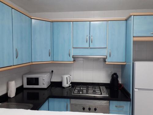 een keuken met blauwe kasten, een fornuis en een magnetron bij Apartamento Deluxe Yumbo in Playa del Inglés