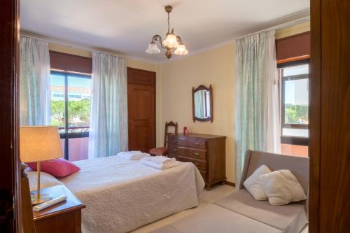 een slaapkamer met een bed, een dressoir en een raam bij Apartamento São Pedro do Mar in Quarteira