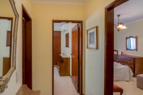 einen Flur, der zu einem Schlafzimmer mit einem Bett und einem Spiegel führt in der Unterkunft Apartamento São Pedro do Mar in Quarteira