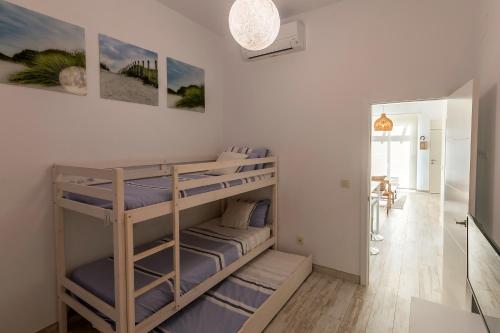 a room with two bunk beds and a hallway at Bajo con Jardin y Piscina cerca de la Playa Dos Dormitorios in Tarifa