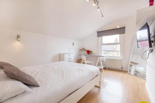a white bedroom with a bed and a desk at Tooting Broadway Studios & Rooms by PrimeCityHosts in London
