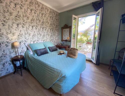 a bedroom with a bed with blue sheets and a window at Hotel Le Ponteil in Antibes