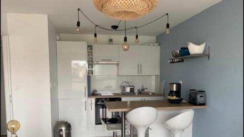 une cuisine avec des placards blancs, une table et des tabourets dans l'établissement Le grand Bleu, à Wimereux