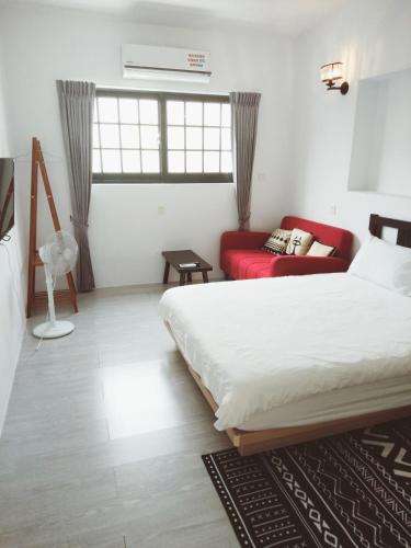 a bedroom with a bed and a red couch at 小時公館城西 in Yuli