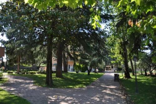 a path in a park with trees and a bench at Park Hotel Villamaria in Pavona
