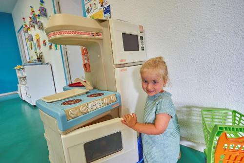 a little girl standing next to a toy stove at Résidence Château de Salles in Salles