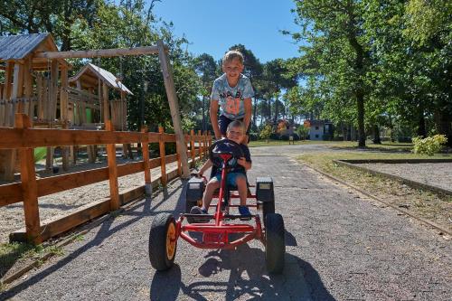 a child standing on top of a boy on a toy car at Résidence Château de Salles in Salles