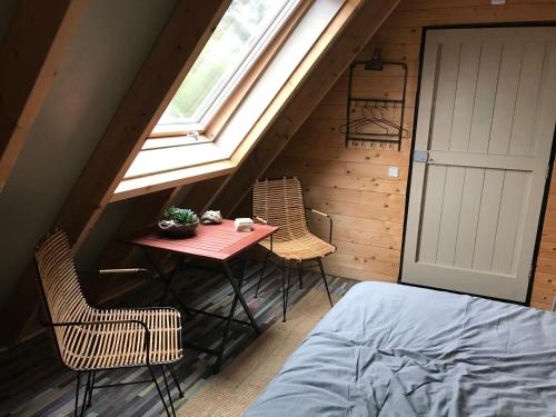 a attic room with a table and chairs and a window at T’ Hogeland Ainrom in Eenrum