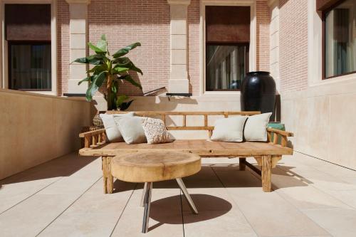 a wooden bench with pillows on a patio at Ansares Hotel in Tarancón