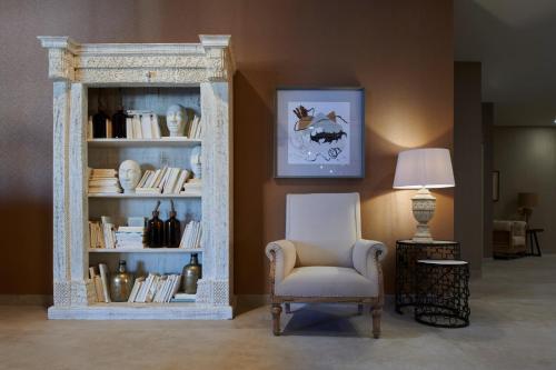 a room with a chair and a book shelf with books at Ansares Hotel in Tarancón