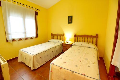 two beds in a room with yellow walls at Aventura & Relax Cabañas Peña la Higuera in Villalba de la Sierra