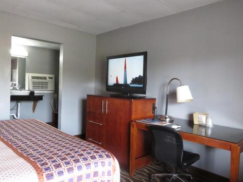 a hotel room with a bed and a desk and a television at Travelodge by Wyndham Walterboro in Walterboro