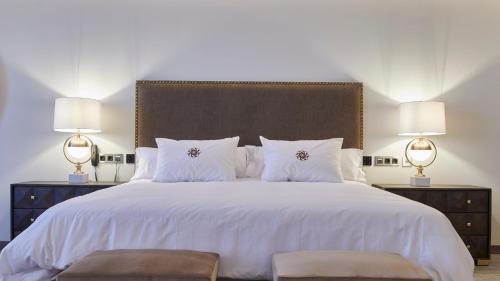 a bedroom with a large white bed with two lamps at Ansares Hotel in Tarancón
