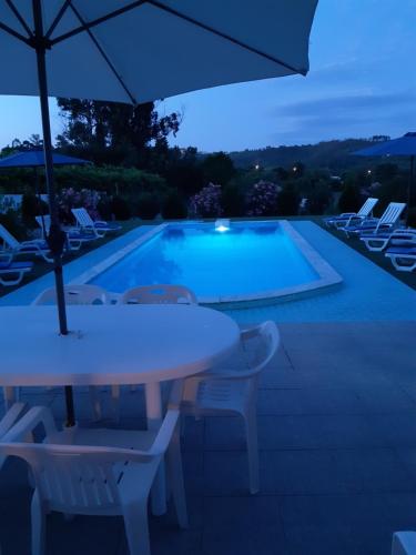 a pool with a table and chairs and an umbrella at As casinhas dos meus Avós by Quinta do Paço in Amarante