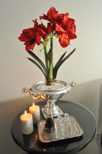 a vase with red flowers on a table with candles at Adato Guesthouse in Potchefstroom