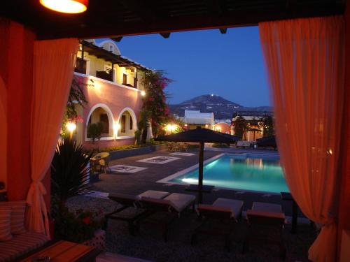 a pool with chairs and an umbrella in front of a building at Abelonas Village in Megalokhori