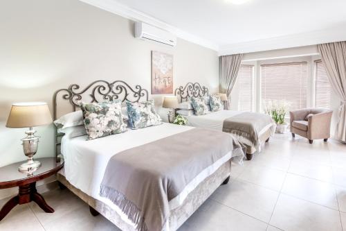 a bedroom with two beds and a chair at Adato Guesthouse in Potchefstroom