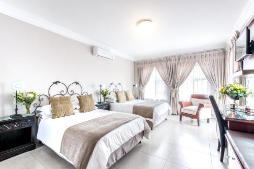 a hotel room with two beds and a chair at Adato Guesthouse in Potchefstroom