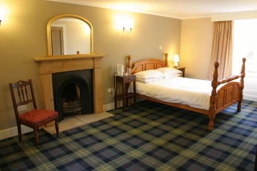 a bedroom with a bed and a fireplace and a mirror at Bankfoot Inn in Bankfoot