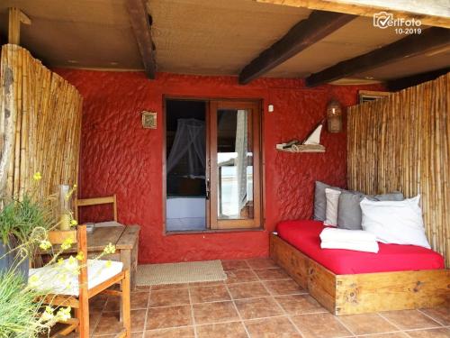 a bedroom with a red room with a bed and a window at La Perla del Cabo in Cabo Polonio