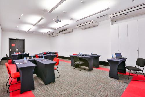 a room with black tables and red chairs at Radisson RED Campinas in Campinas