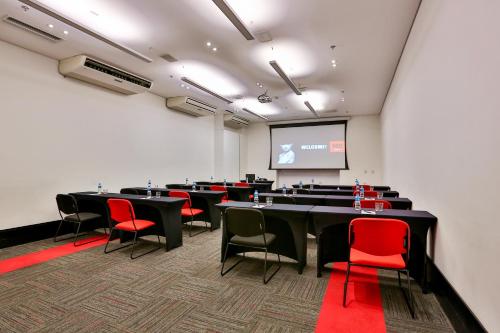 a conference room with tables and chairs and a screen at Radisson RED Campinas in Campinas