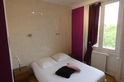 a bedroom with a white bed with a pink pillow on it at le relais des forêts in Blessac