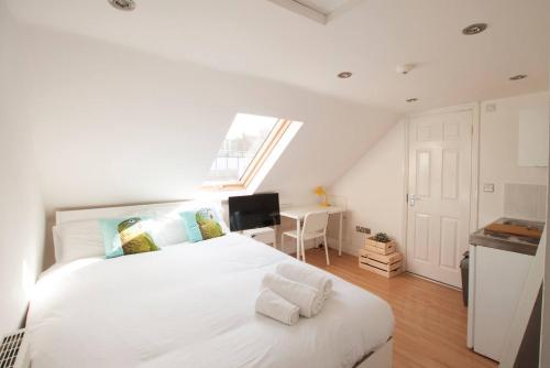 a bedroom with a large white bed with a window at Tooting Broadway Studios & Rooms by DC London Rooms in London