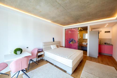 a bedroom with a bed and a desk and pink chairs at A9 Luxury Balatonudvari in Balatonudvari