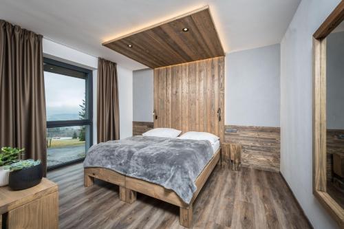 a bedroom with a bed and a large window at Hotel Královka in Bedřichov