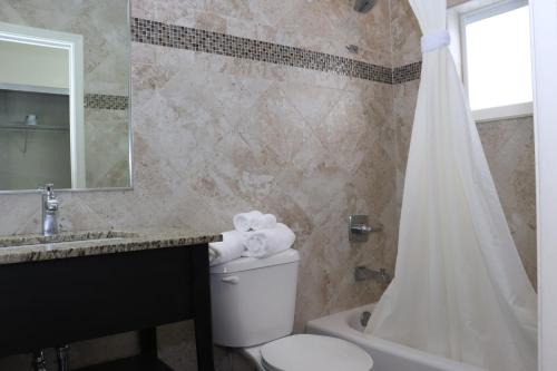 y baño con aseo, lavabo y ducha. en Curtis Inn & Suites en Hollywood