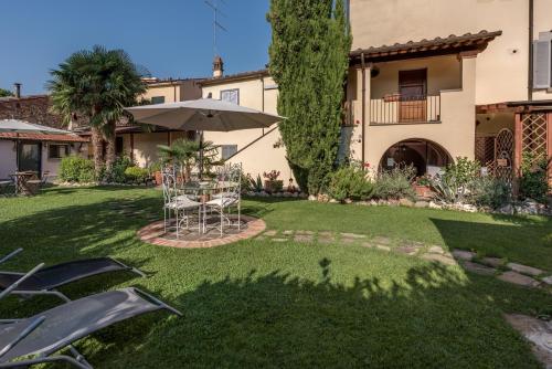 a patio with an umbrella and chairs in a yard at Residence Le Gagli arde in Arezzo