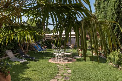 a garden with tables and chairs and a palm tree at Residence Le Gagli arde in Arezzo