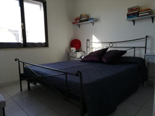 1 dormitorio con 1 cama con edredón azul y ventana en Ca da Ste, en Calasetta