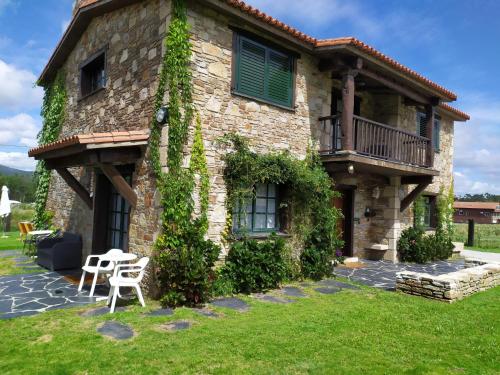 uma casa de pedra com uma mesa e cadeiras em frente em Camiño da Vieira em Padrón