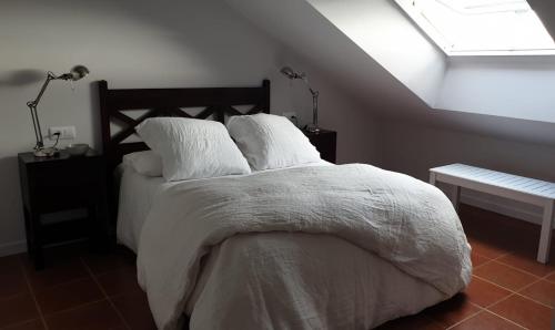 una camera da letto con un letto con lenzuola bianche e una finestra di Ático en Tapia de Casariego con vistas a la playa. a Tapia de Casariego