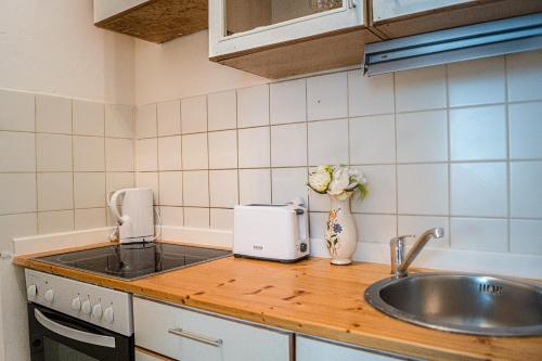 a kitchen counter with a sink and a vase of flowers at Ideal 2BR - Lovely for Longstays in Vienna