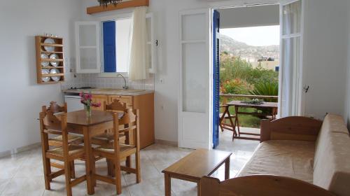 cocina y sala de estar con mesa y sillas en Pleiades Apartments, en Lefkos Karpathou