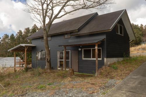 une maison noire avec un arbre en face dans l'établissement Minamiizu Land Hopia - Vacation STAY 83987, à Ihama