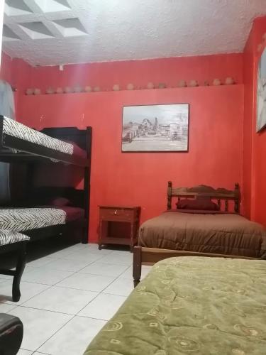 - une chambre avec des murs rouges et 2 lits superposés dans l'établissement Escocie - Quito, à Quito