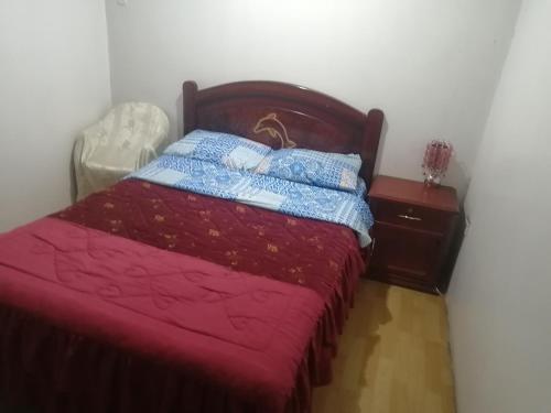 1 dormitorio con cama con colcha roja y mesita de noche en Escocie - Quito, en Quito