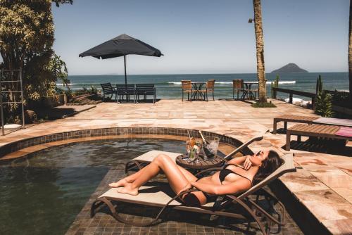 a woman in a bikini laying in a chair next to a pool at Chez Louise et Louis Pé na Areia in Juquei