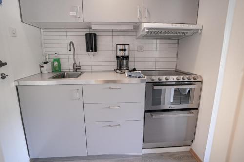 cocina con armarios blancos, fregadero y fogones en Maristova apartment 110, en Filefjell