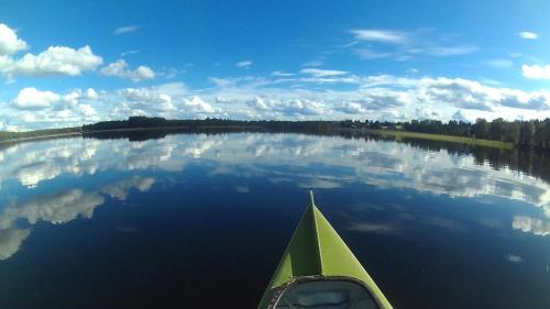 a green kayak on a lake with its reflection in the water at Hugsnäset Semesterstugor och Fiske in Gällö