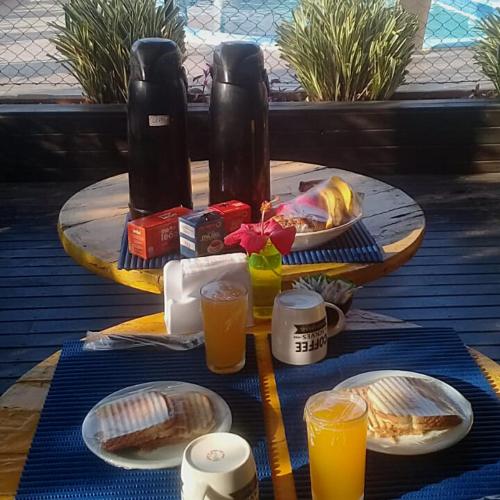 una mesa con platos de comida y vasos de jugo de naranja en Pousada Moçamba Dunas Beach, en Florianópolis