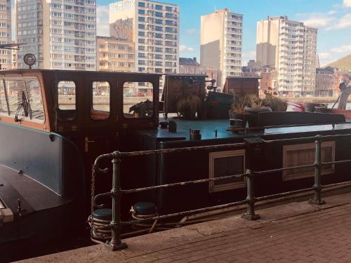 a boat sitting on aarf with buildings in the background at La Cabine du Capitaine in Liège