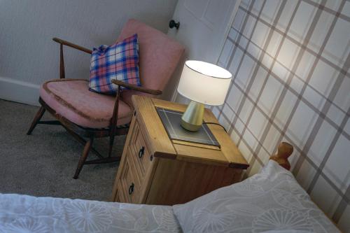 a bedroom with a chair and a lamp on a table at Charming Townhouse on North Coast 500 Route, Wick in Wick